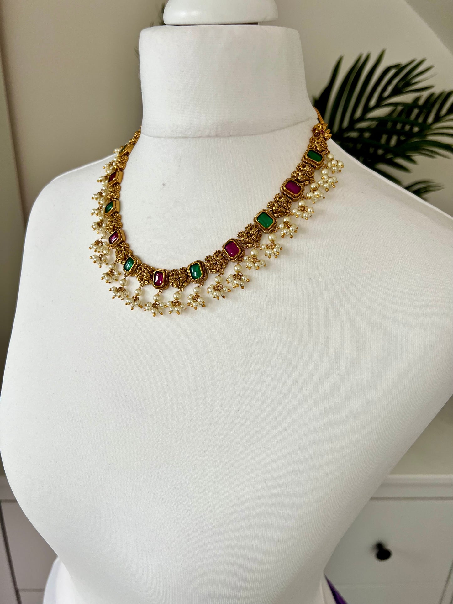 TASHA - Gold plated short necklace with rubygreen stones and dangling ivory pearls, matching jhumkas included N3046