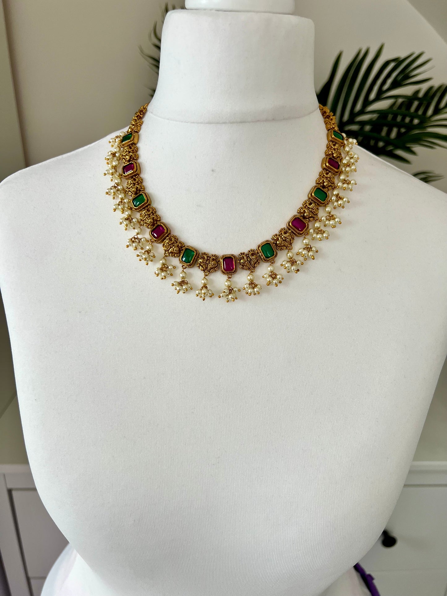 TASHA - Gold plated short necklace with rubygreen stones and dangling ivory pearls, matching jhumkas included N3046